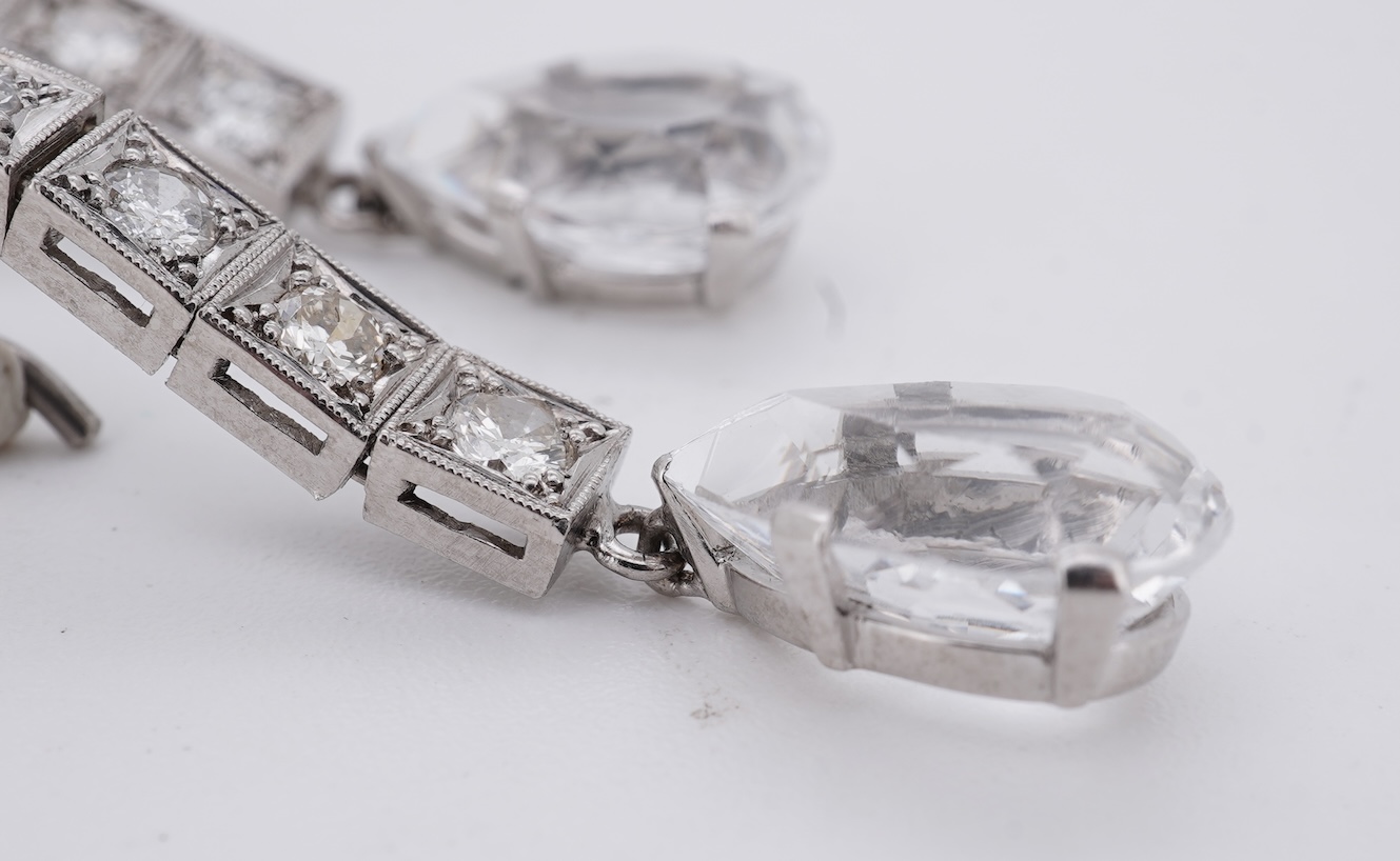 A pair of white metal and four stone diamond set earrings, each with a cubic zirconia pear shaped drop, overall 42mm.